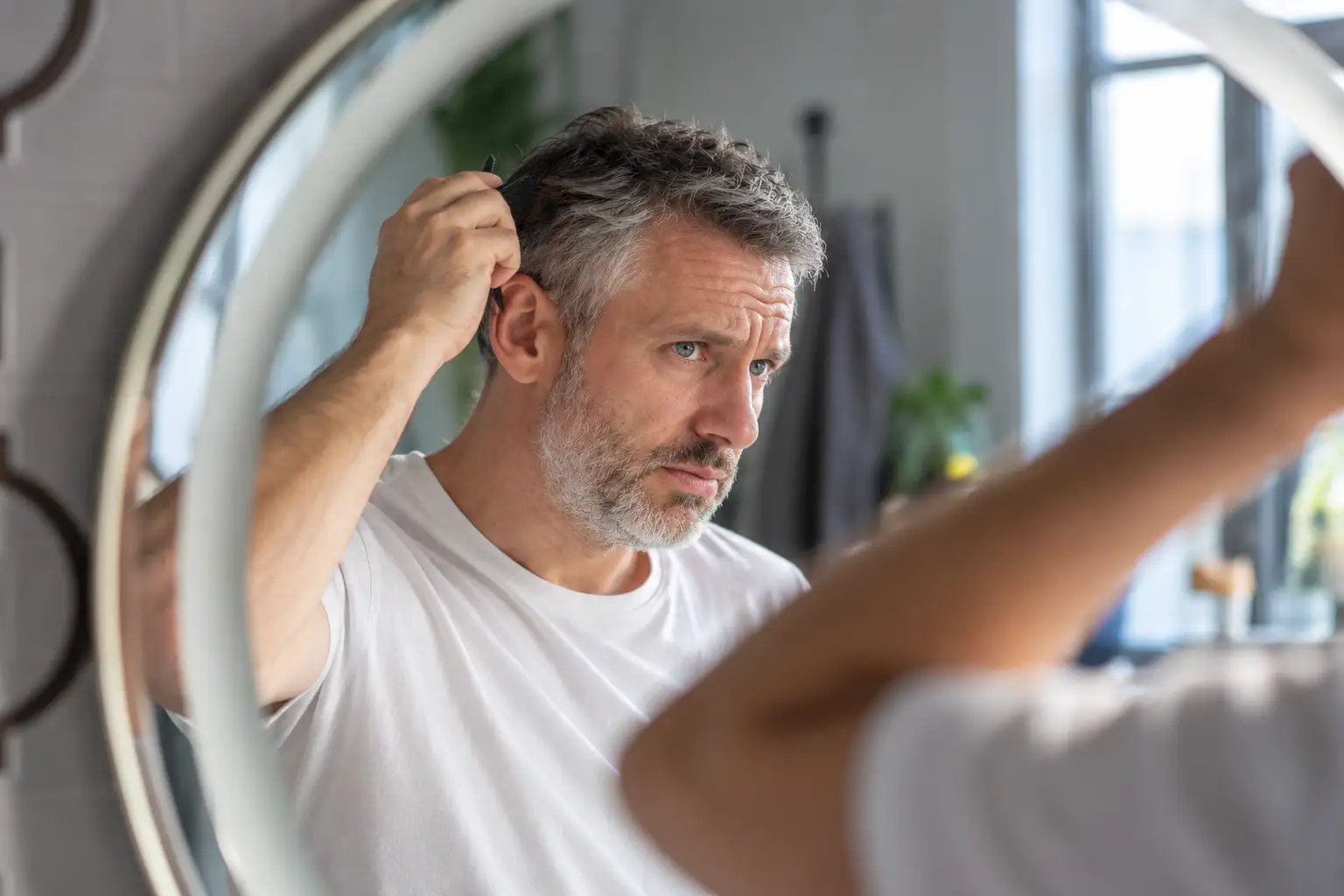 Uomo allo specchio — capelli bianchi alle radici